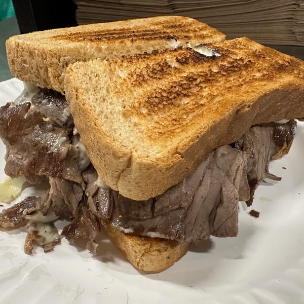 Close-up of a hearty roast beef sandwich on toasted bread with melted cheese.