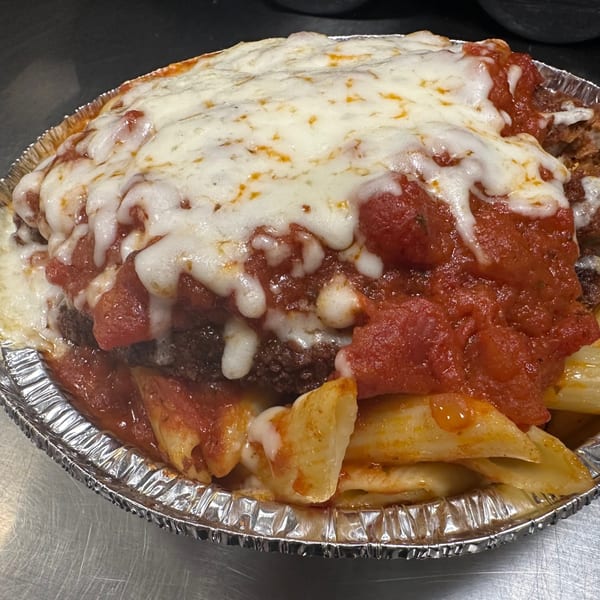 Baked ziti with melted mozzarella cheese and red sauce in a foil pan from Eddies Pizza.