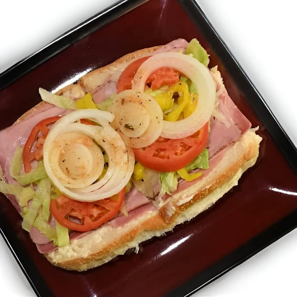 A large Eddies Pizza & Catering sub sandwich with ham, lettuce, tomatoes, onions, and peppers.