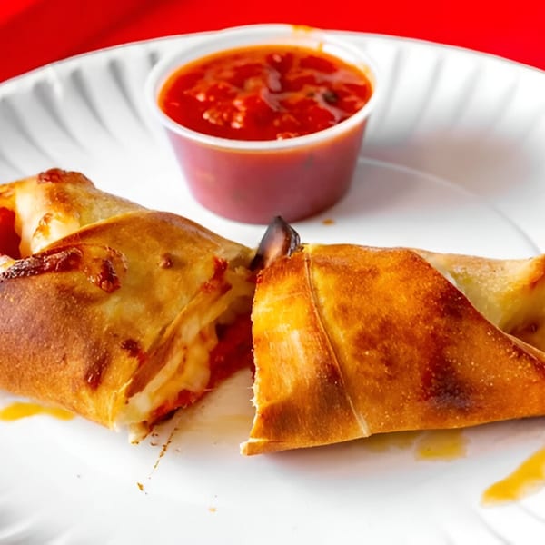 Two golden-brown calzones, one cut open to reveal melted cheese and sauce, with a side of marinara.