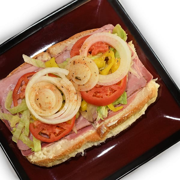 A large Eddies Pizza & Catering sub sandwich with ham, lettuce, tomatoes, onions, and peppers.
